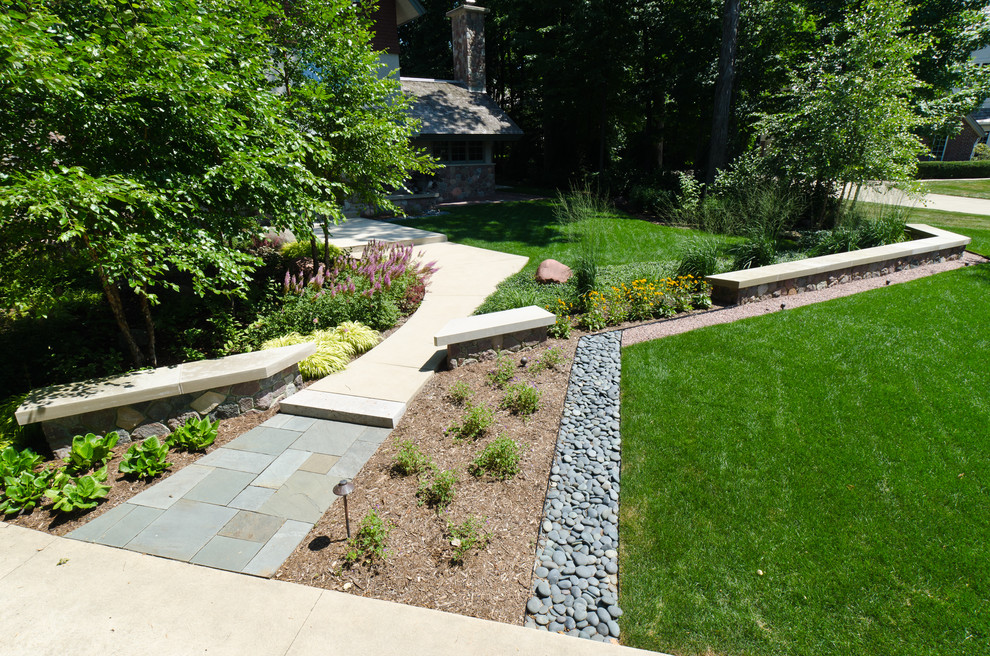 This is an example of a large arts and crafts front yard garden in Milwaukee with natural stone pavers.