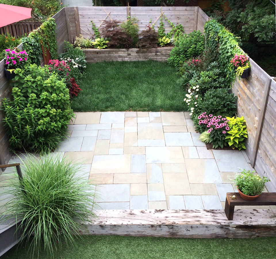 This is an example of a small modern backyard full sun driveway for fall in New York with natural stone pavers and a container garden.
