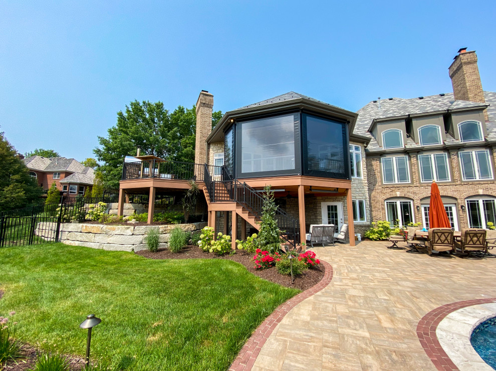 Photo of a large backyard and first floor deck in St Louis with with privacy feature, a roof extension and metal railing.