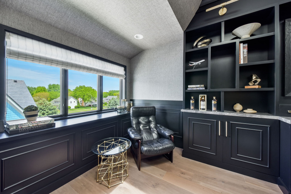 This is an example of a large transitional home office in Chicago with black walls, no fireplace, a built-in desk, beige floor and wallpaper.