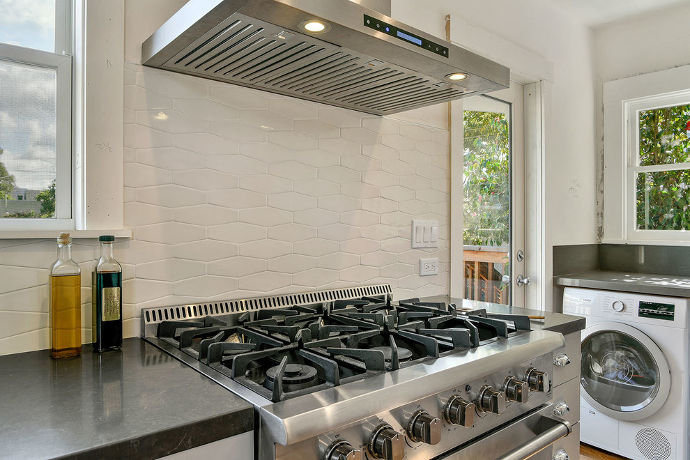 Inspiration for a mid-sized transitional galley light wood floor and beige floor enclosed kitchen remodel in San Francisco with an undermount sink, flat-panel cabinets, beige cabinets, quartz countertops, white backsplash, ceramic backsplash, stainless steel appliances and no island