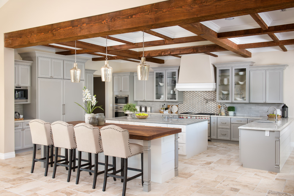 Inspiration for a large mediterranean l-shaped open plan kitchen in Phoenix with grey cabinets, wood benchtops, grey splashback, stainless steel appliances, multiple islands, beige floor, a farmhouse sink, recessed-panel cabinets, ceramic splashback and ceramic floors.