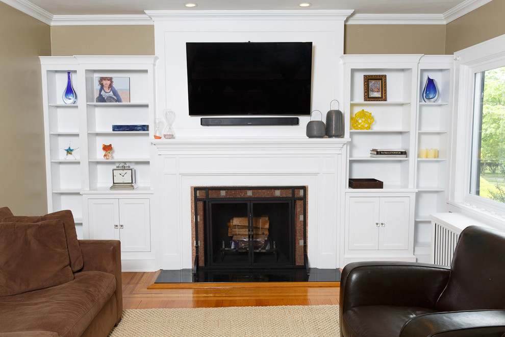 Photo of a mid-sized transitional enclosed living room in New York with a library, beige walls, medium hardwood floors, a standard fireplace, a tile fireplace surround and a wall-mounted tv.