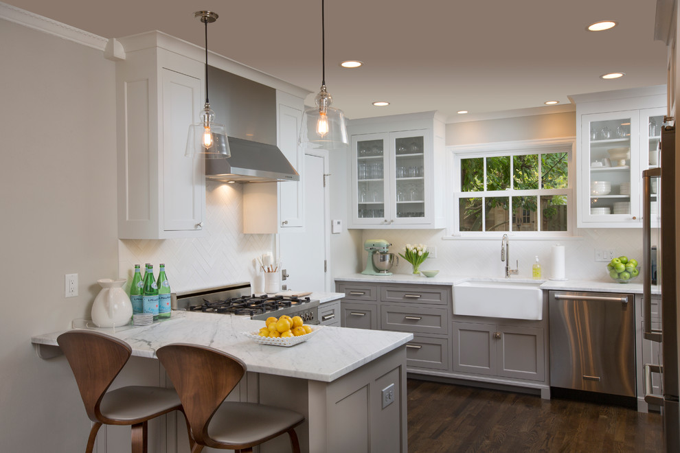 Transitional u-shaped dark wood floor kitchen photo in Columbus with a farmhouse sink, shaker cabinets, gray cabinets, white backsplash, stainless steel appliances and a peninsula