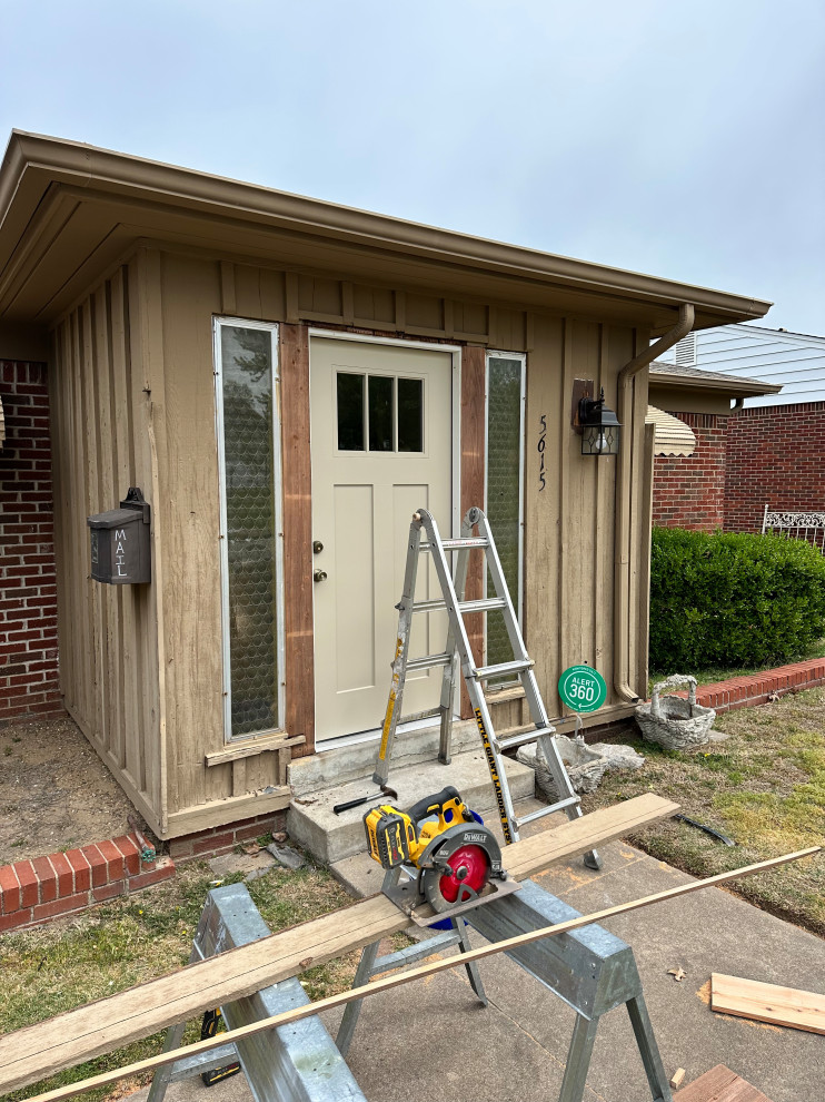 Cette image montre un grand porche d'entrée de maison avant craftsman avec un garde-corps en verre.