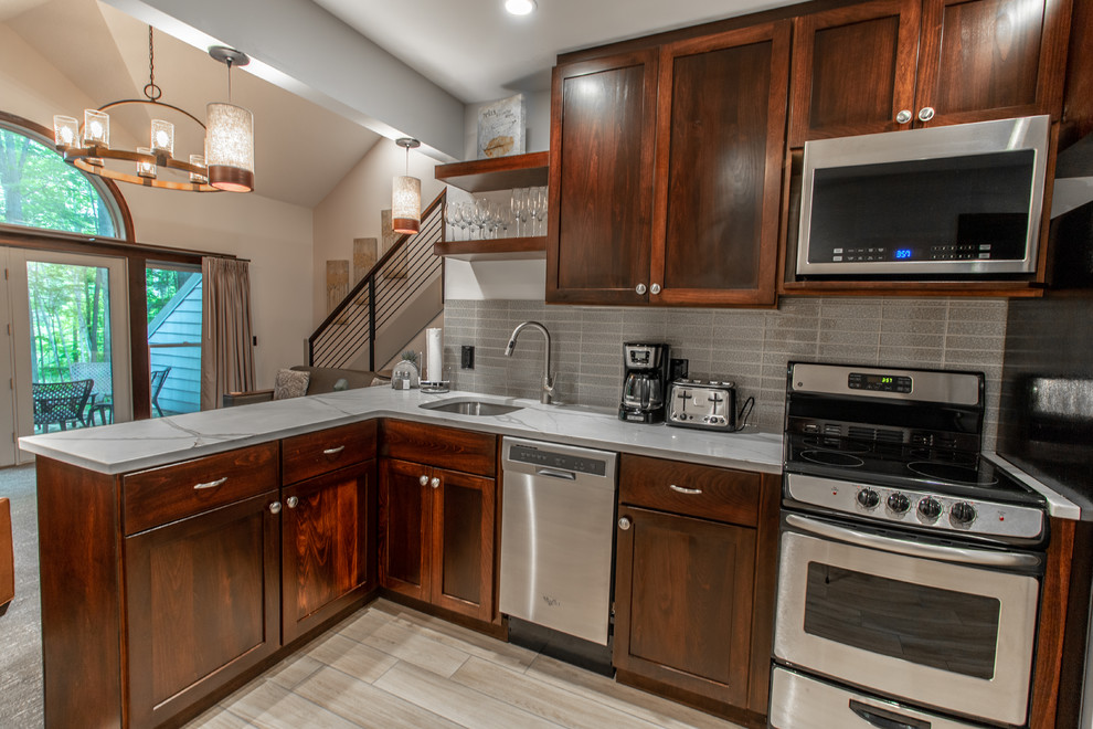 Open concept kitchen - mid-sized transitional l-shaped ceramic tile and beige floor open concept kitchen idea with an undermount sink, shaker cabinets, dark wood cabinets, quartz countertops, gray backsplash, ceramic backsplash, stainless steel appliances, no island and white countertops