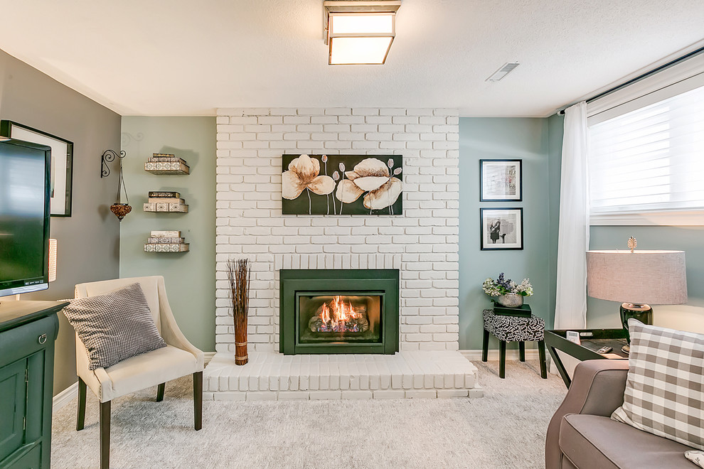 This is an example of a small contemporary look-out basement in Toronto with green walls, carpet, a standard fireplace, a brick fireplace surround and grey floor.