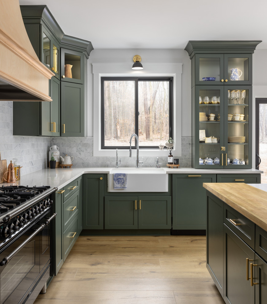Example of a large classic u-shaped light wood floor and beige floor open concept kitchen design in Detroit with a farmhouse sink, shaker cabinets, green cabinets, quartz countertops, white backsplash, marble backsplash, stainless steel appliances, an island and white countertops