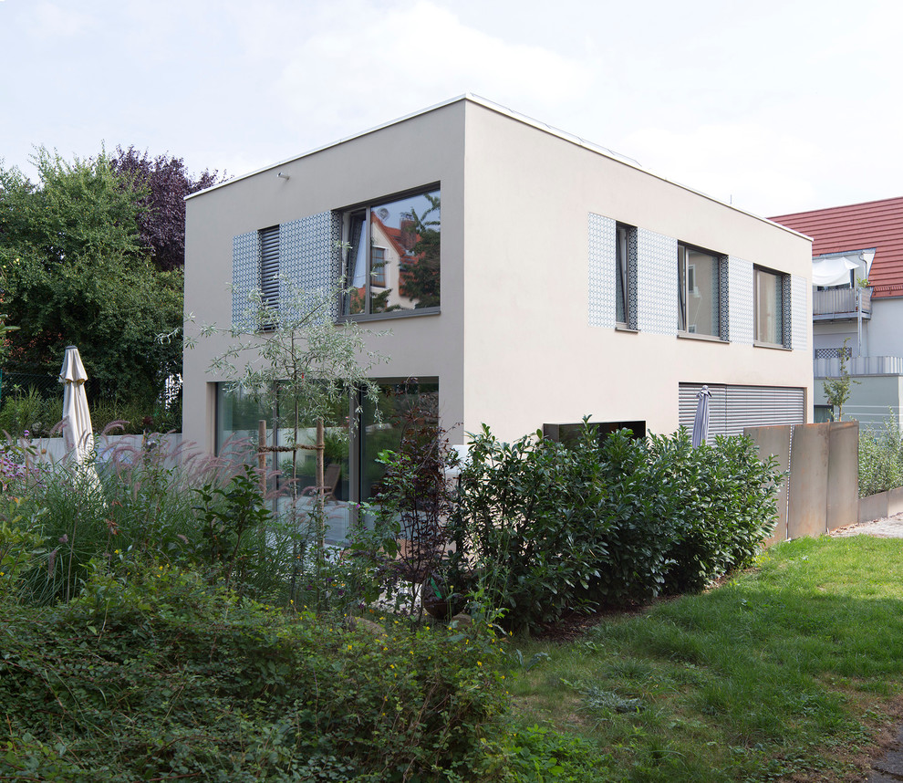 Design ideas for a mid-sized contemporary two-storey stucco beige house exterior in Munich with a flat roof.