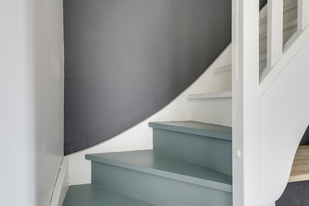 Photo of a mid-sized mediterranean painted wood curved staircase in Paris with painted wood risers and wood railing.