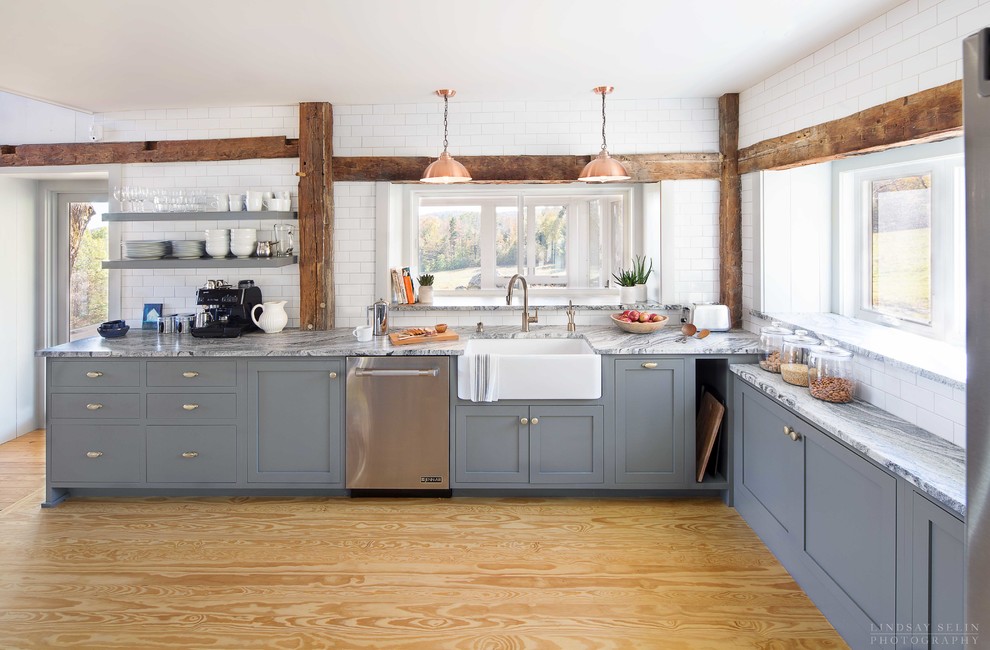 This is an example of a mid-sized contemporary eat-in kitchen in Boston with a farmhouse sink, shaker cabinets, grey cabinets, granite benchtops, white splashback, subway tile splashback, stainless steel appliances, light hardwood floors, no island, brown floor and multi-coloured benchtop.