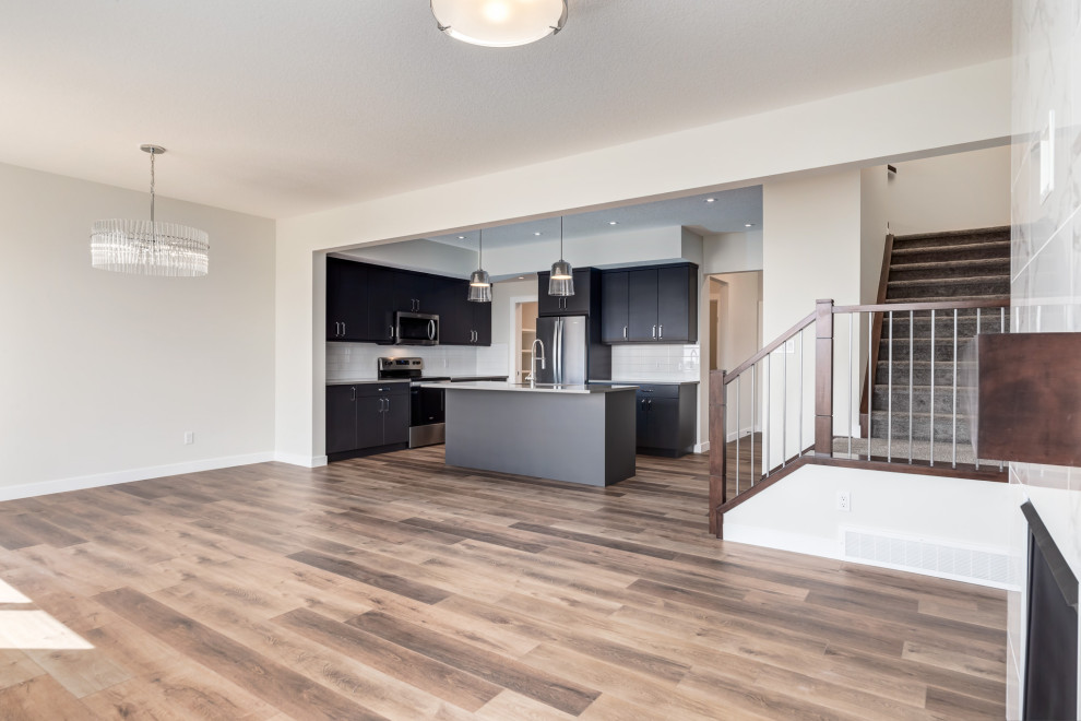Offenes Modernes Wohnzimmer mit weißer Wandfarbe, Vinylboden, gefliester Kaminumrandung, Multimediawand und braunem Boden in Calgary