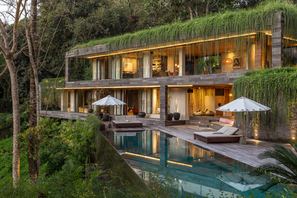 Inspiration for a tropical two-storey grey house exterior in Other with a flat roof and a green roof.
