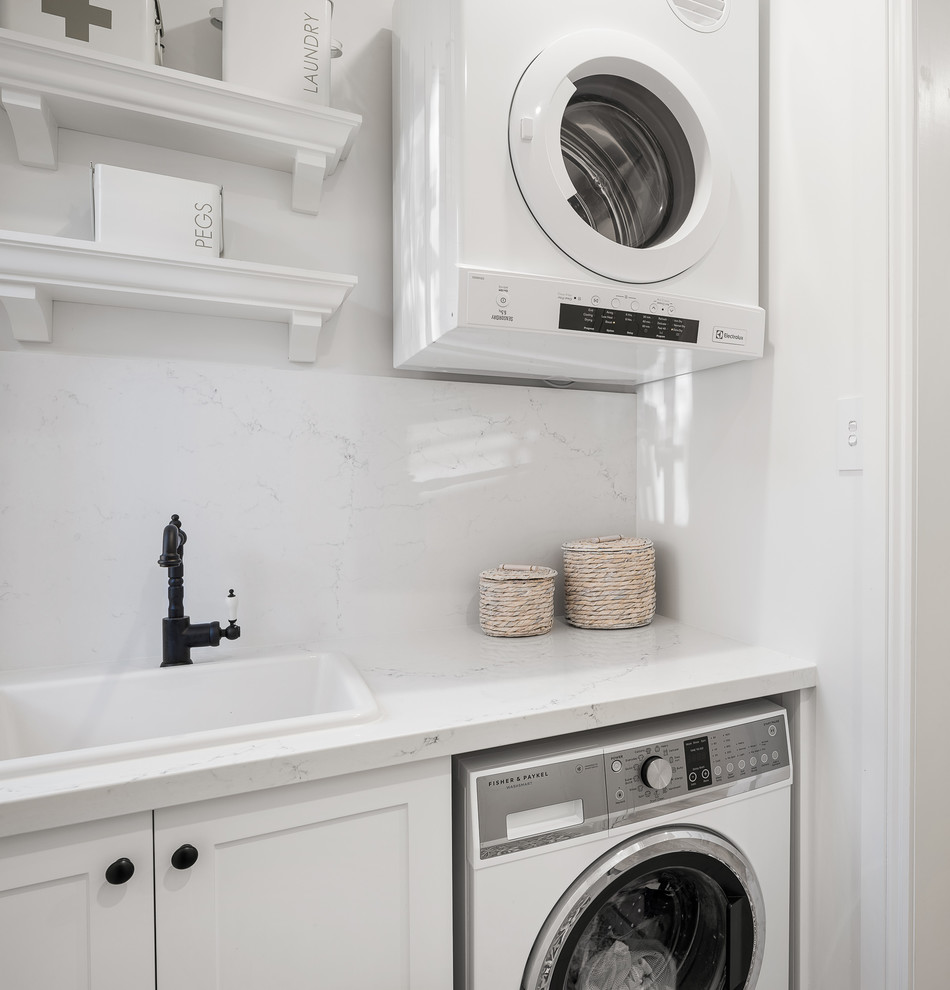 Photo of a small traditional single-wall dedicated laundry room in Sydney with a farmhouse sink, shaker cabinets, white cabinets, marble benchtops, white walls, ceramic floors, a side-by-side washer and dryer, multi-coloured floor and white benchtop.