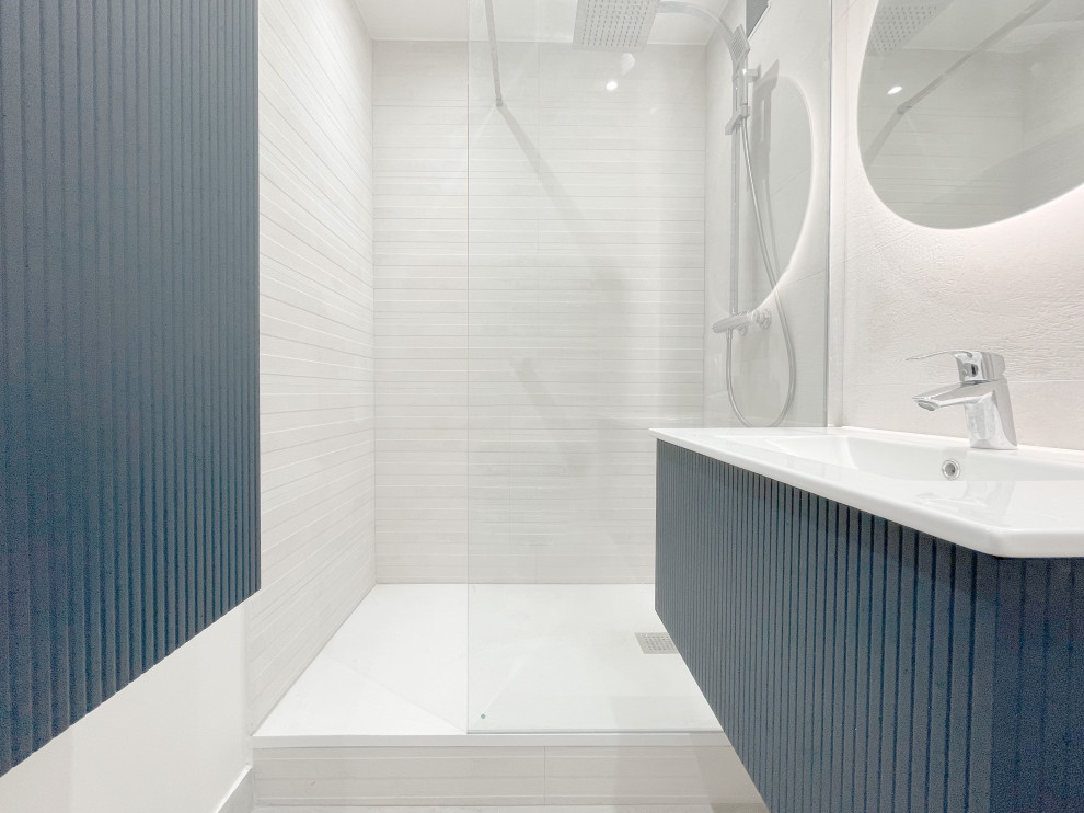 Cette photo montre une petite salle de bain principale moderne avec un placard à porte affleurante, des portes de placard bleues, une douche à l'italienne, un carrelage gris, un mur gris, un lavabo suspendu, aucune cabine, meuble simple vasque, meuble-lavabo suspendu, un plafond décaissé et un mur en parement de brique.