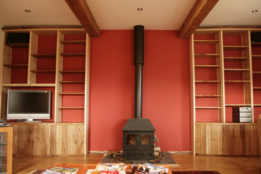 Inspiration for a mid-sized contemporary open concept living room in Other with red walls, medium hardwood floors, a wood stove and a built-in media wall.