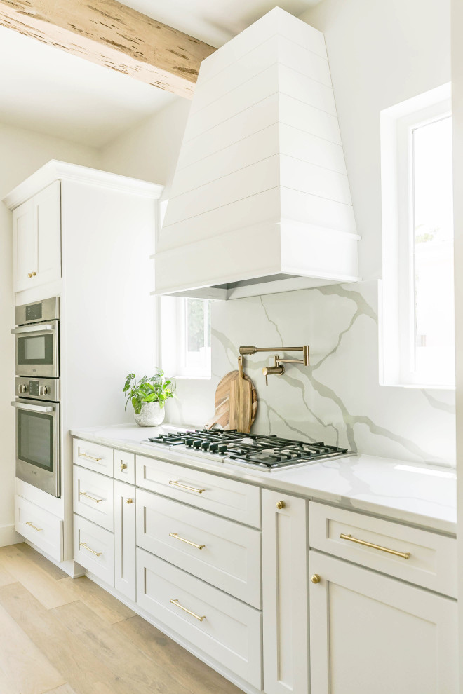 Foto på ett maritimt vit kök, med skåp i shakerstil, vita skåp, bänkskiva i kvarts, vitt stänkskydd och ljust trägolv