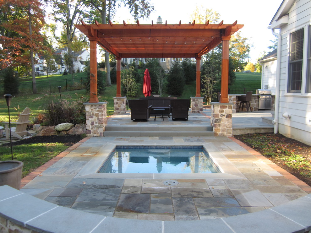 Photo of a mid-sized country backyard patio in Philadelphia with a fire feature, natural stone pavers and a pergola.