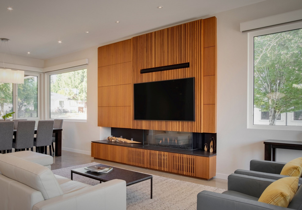 Modern living room in Vancouver with concrete floors, a ribbon fireplace, a wood fireplace surround, a built-in media wall, grey floor and panelled walls.