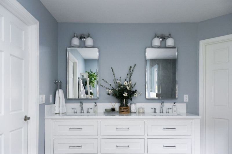 Corner shower - mid-sized transitional master multicolored tile and ceramic tile vinyl floor, brown floor and double-sink corner shower idea with shaker cabinets, white cabinets, blue walls, an undermount sink, quartz countertops, a hinged shower door, white countertops and a built-in vanity