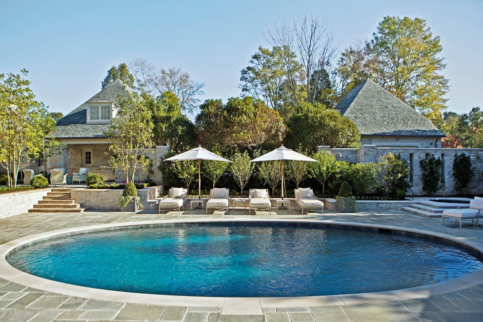 Mid-sized traditional backyard round lap pool in Charlotte with natural stone pavers and a hot tub.