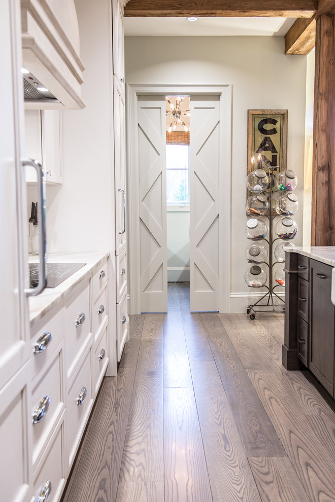 Design ideas for a large country single-wall eat-in kitchen in St Louis with a farmhouse sink, shaker cabinets, white cabinets, marble benchtops, white splashback, subway tile splashback, white appliances, medium hardwood floors and with island.