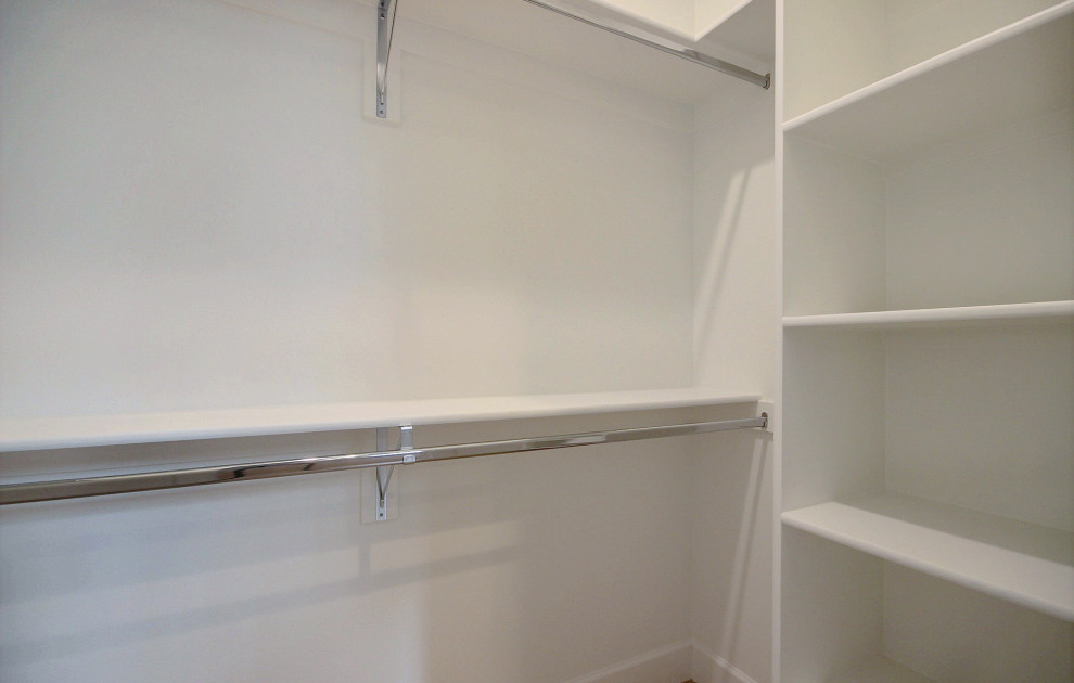 This is an example of a large country gender-neutral walk-in wardrobe in Portland with open cabinets, white cabinets, light hardwood floors and beige floor.