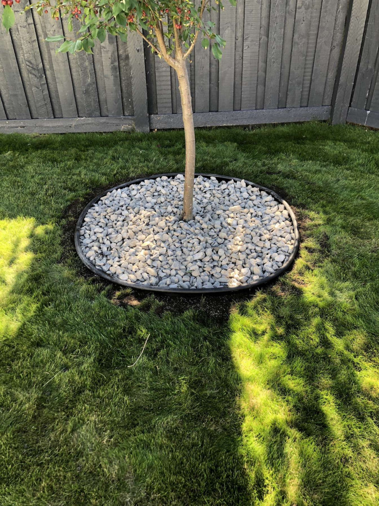 Inspiration for a mid-sized drought-tolerant backyard river rock flower bed in Edmonton.