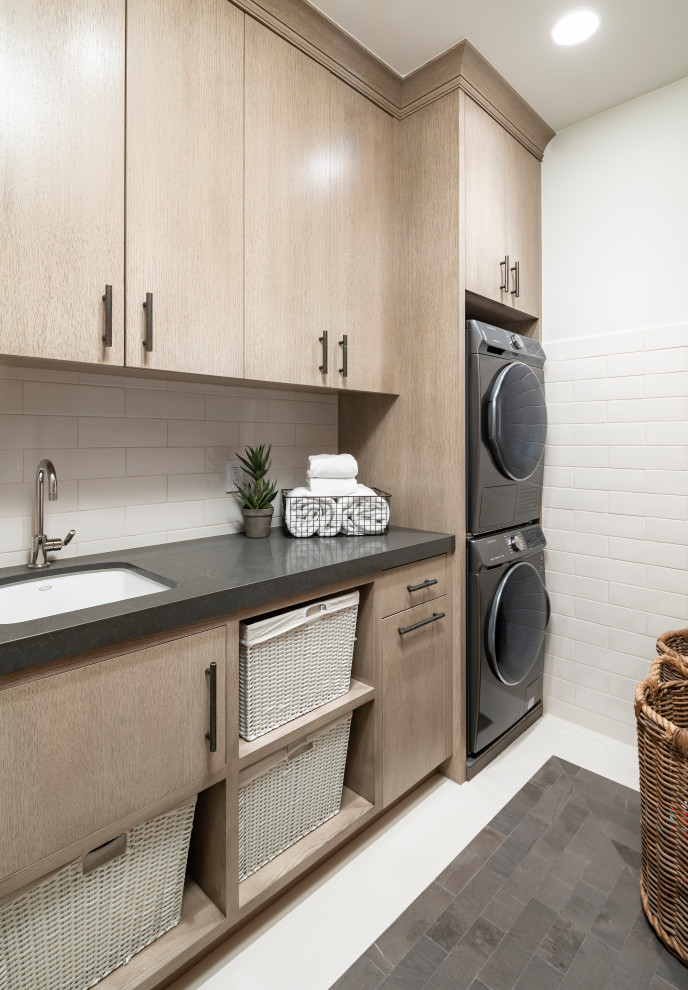 Large country galley dedicated laundry room in Salt Lake City with an undermount sink, flat-panel cabinets, beige cabinets, granite benchtops, white walls, slate floors, a stacked washer and dryer, grey floor and grey benchtop.