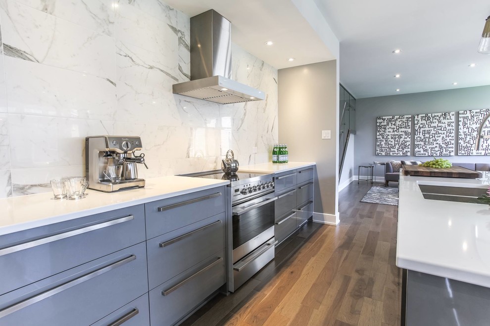 Photo of a mid-sized modern galley open plan kitchen in Ottawa with an undermount sink, flat-panel cabinets, white cabinets, quartzite benchtops, white splashback, stone slab splashback, stainless steel appliances, light hardwood floors, with island and beige floor.