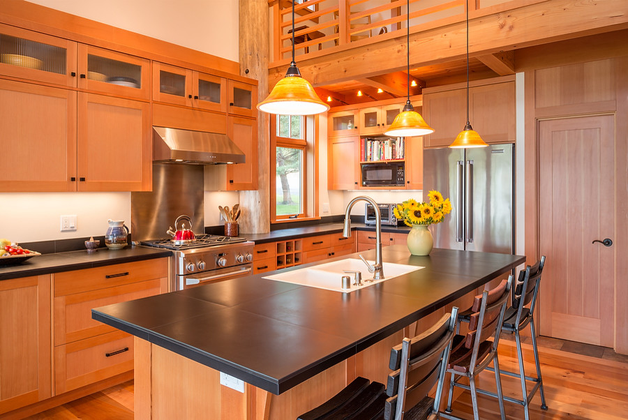 This is an example of a large modern l-shaped open plan kitchen in Seattle with a double-bowl sink, recessed-panel cabinets, light wood cabinets, tile benchtops, black splashback, stone tile splashback, stainless steel appliances, medium hardwood floors and with island.