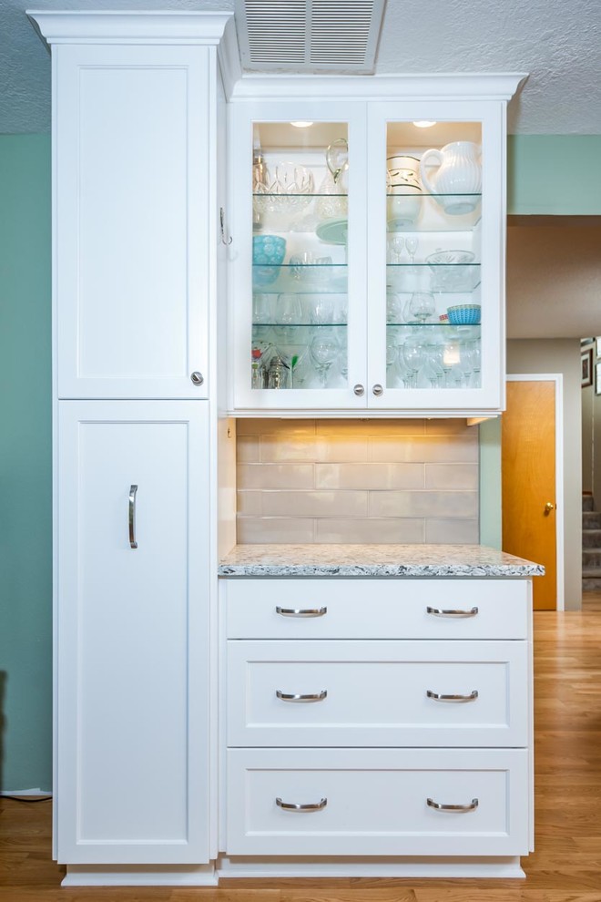Inspiration for a mid-sized traditional l-shaped eat-in kitchen in Portland with an undermount sink, shaker cabinets, white cabinets, quartzite benchtops, grey splashback, stone tile splashback, stainless steel appliances, with island, brown floor, white benchtop and vinyl floors.
