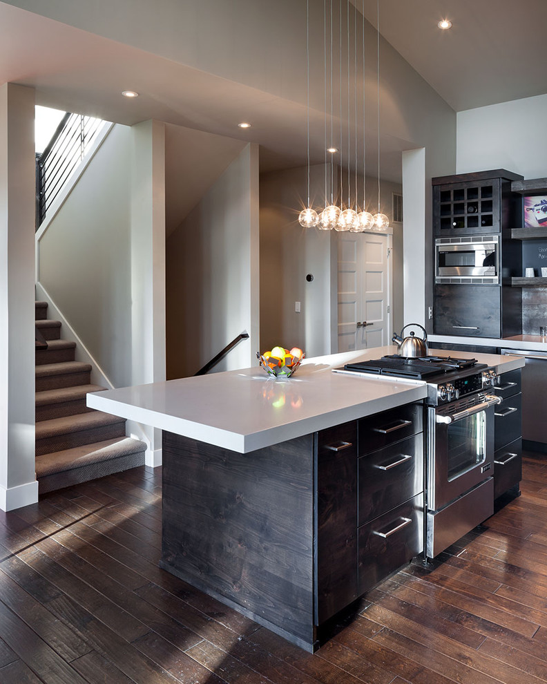 Photo of a large contemporary l-shaped eat-in kitchen in Portland with stainless steel appliances, dark wood cabinets, quartz benchtops, a farmhouse sink, flat-panel cabinets, dark hardwood floors and with island.