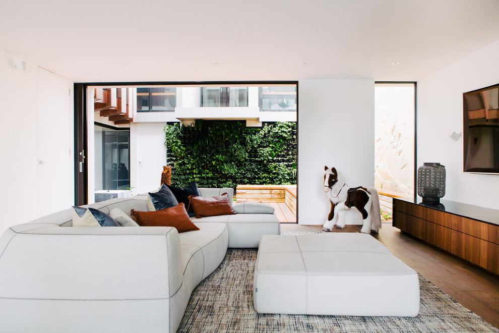 Expansive contemporary gender-neutral kids' playroom in Sydney with white walls, dark hardwood floors and brown floor.