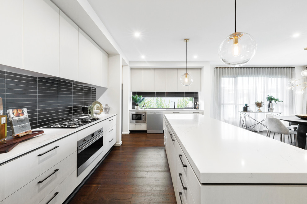 Photo of a contemporary l-shaped kitchen in Melbourne with flat-panel cabinets, white cabinets, stainless steel appliances, dark hardwood floors, with island, brown floor and white benchtop.