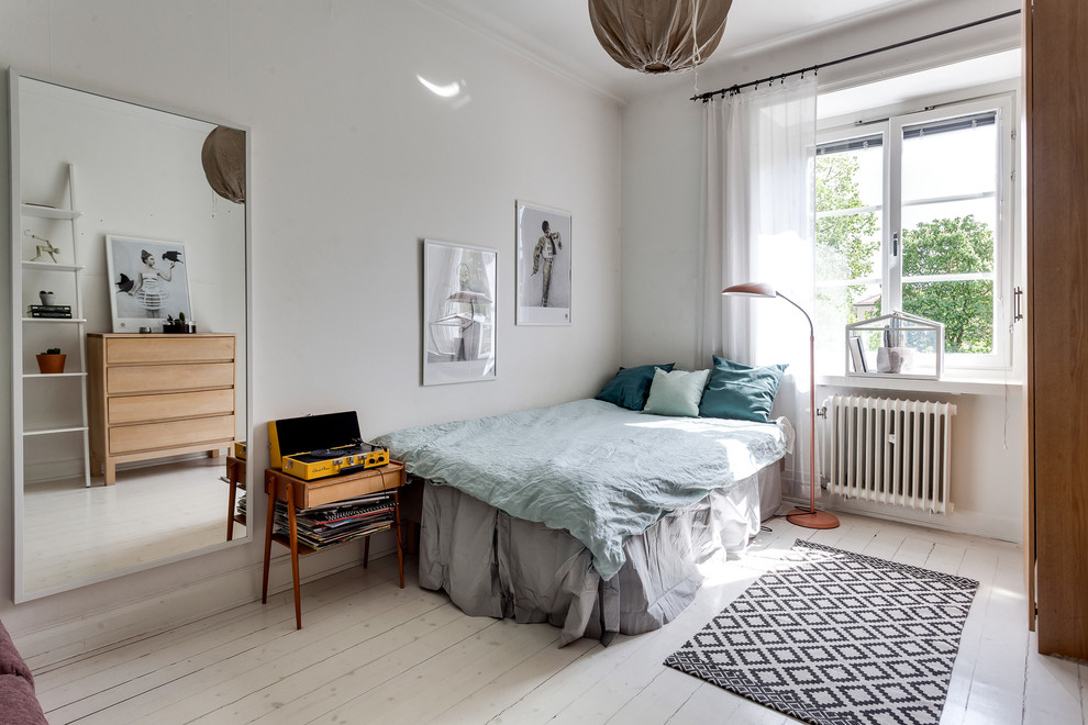 Photo of a mid-sized scandinavian guest bedroom in Stockholm with white walls, light hardwood floors and no fireplace.