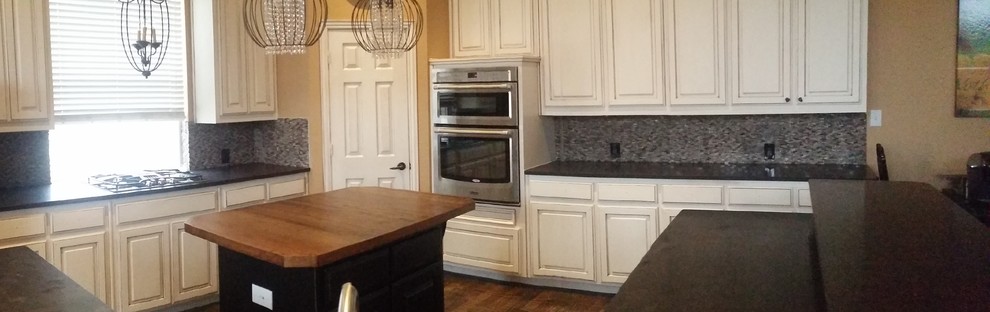 Inspiration for a large transitional brown floor open concept kitchen remodel in Dallas with an undermount sink, raised-panel cabinets, white cabinets, granite countertops, gray backsplash, stone tile backsplash, stainless steel appliances and an island