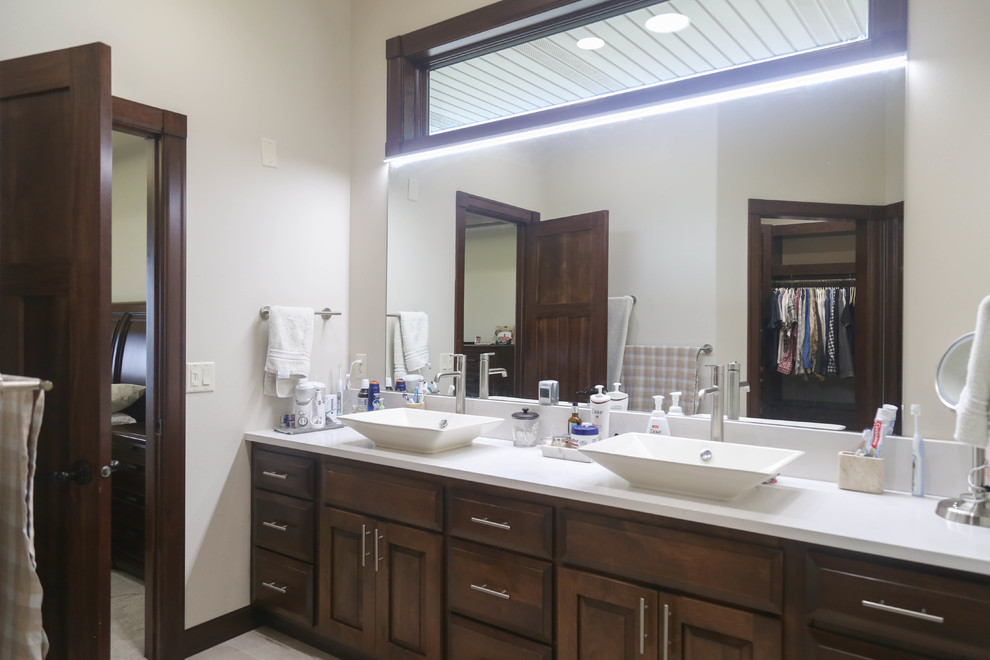 Example of a mid-sized transitional master beige tile and porcelain tile porcelain tile and beige floor alcove shower design with raised-panel cabinets, medium tone wood cabinets, a two-piece toilet, white walls, a vessel sink, quartzite countertops and a hinged shower door