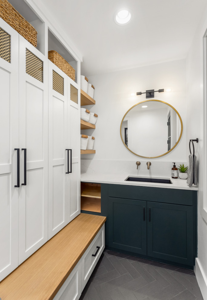 Design ideas for a mid-sized transitional galley utility room in Los Angeles with a drop-in sink, shaker cabinets, blue cabinets, quartz benchtops, white walls, ceramic floors, a concealed washer and dryer, grey floor and white benchtop.