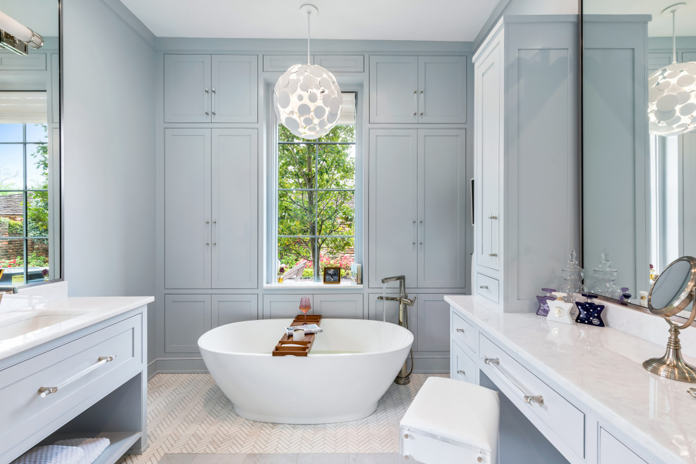This is an example of a large master bathroom in New Orleans with recessed-panel cabinets, blue cabinets, a freestanding tub, a corner shower, a one-piece toilet, blue walls, mosaic tile floors, an undermount sink, quartzite benchtops, white floor, a hinged shower door, white benchtops, a niche, a double vanity and a built-in vanity.