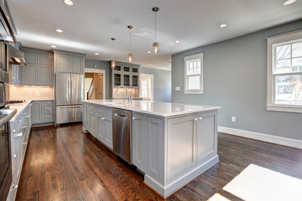 This is an example of a mid-sized arts and crafts l-shaped open plan kitchen in DC Metro with a single-bowl sink, beaded inset cabinets, grey cabinets, quartzite benchtops, white splashback, mosaic tile splashback, white appliances, medium hardwood floors and with island.