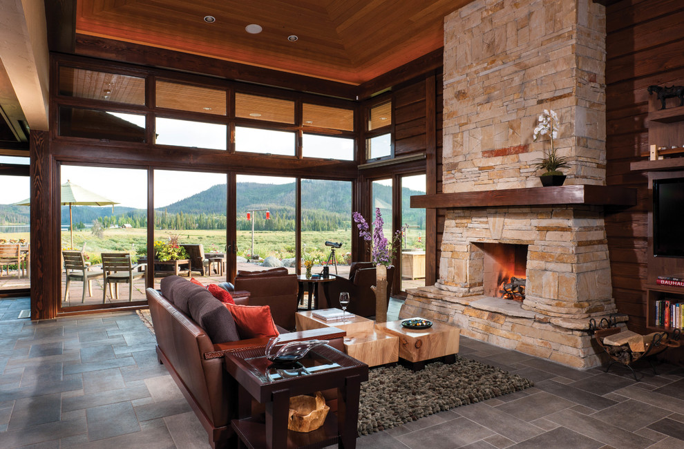 Large modern open concept living room in Boise with brown walls, a standard fireplace, a stone fireplace surround and a wall-mounted tv.