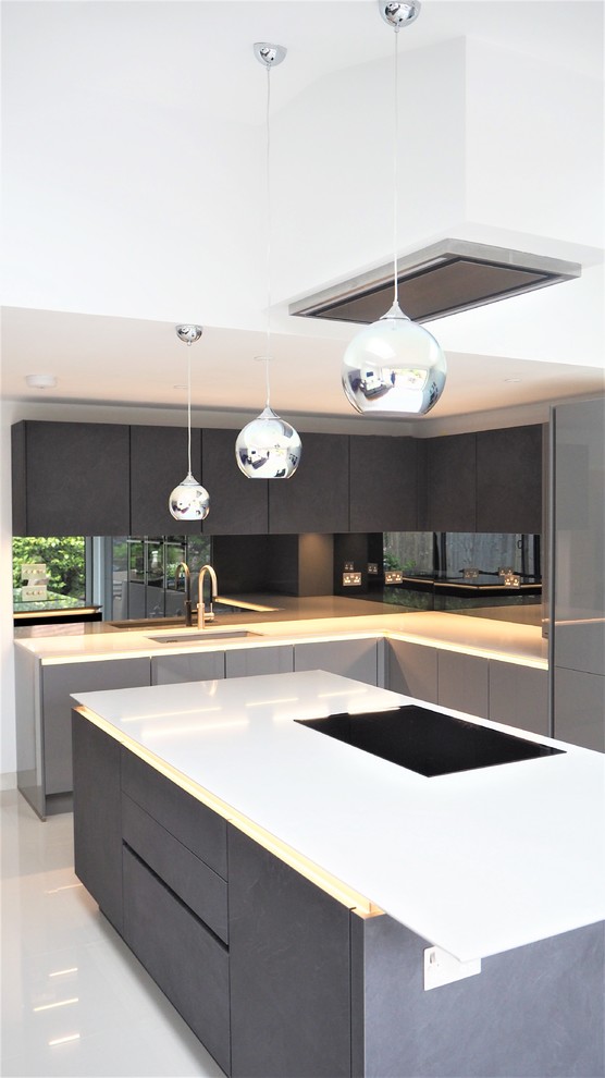 Large modern l-shaped open plan kitchen in London with a single-bowl sink, flat-panel cabinets, black cabinets, granite benchtops, black splashback, with island, white floor and white benchtop.