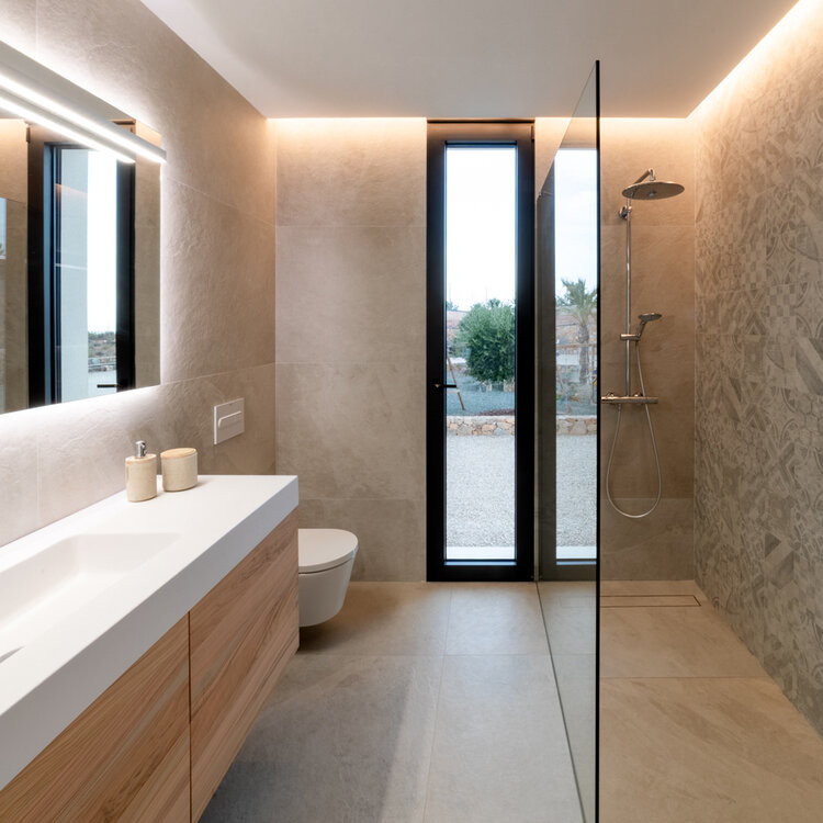 Kleines Modernes Duschbad mit Glasfronten, weißen Schränken, offener Dusche, beigen Fliesen, beiger Wandfarbe, offener Dusche, weißer Waschtischplatte, Einzelwaschbecken und freistehendem Waschtisch in Valencia