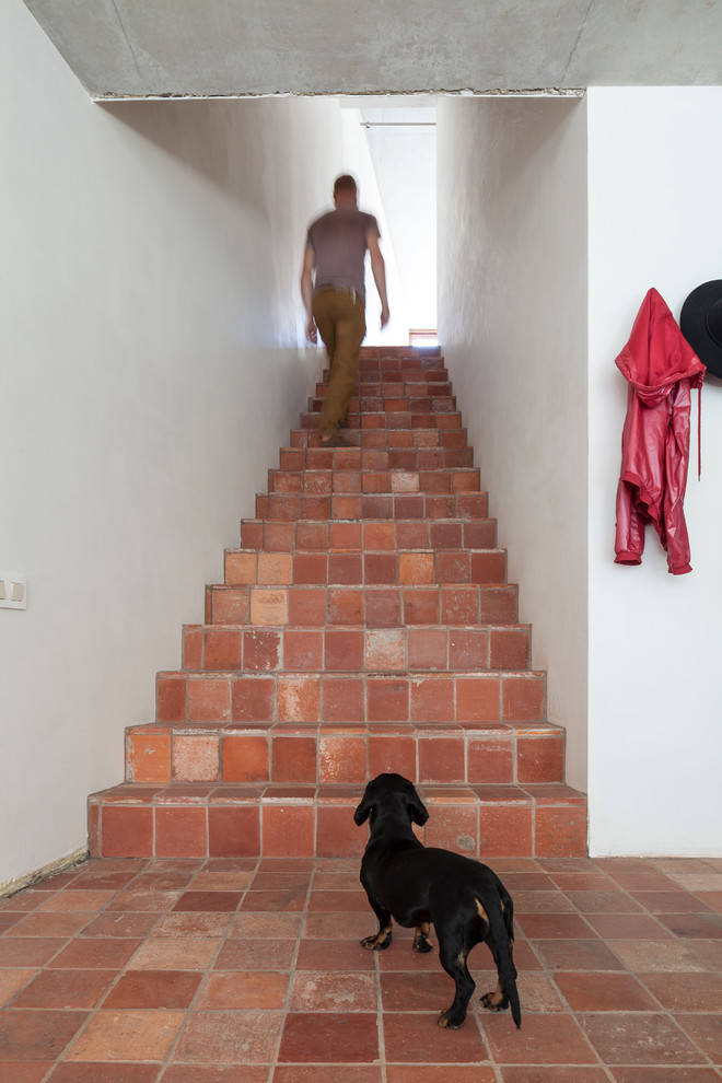 Design ideas for an industrial terracotta staircase in Other with terracotta risers.