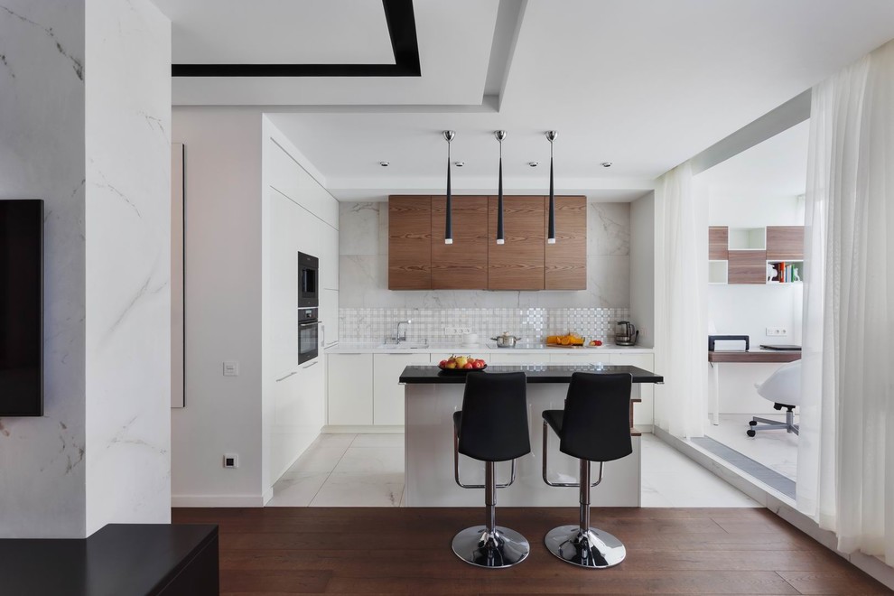 This is an example of a mid-sized contemporary l-shaped open plan kitchen in Yekaterinburg with an undermount sink, flat-panel cabinets, white cabinets, solid surface benchtops, white splashback, porcelain splashback, with island, white benchtop, white floor and black appliances.