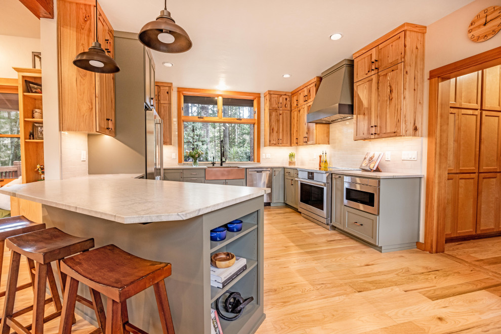 Inspiration for a large rustic u-shaped light wood floor and brown floor eat-in kitchen remodel with a farmhouse sink, shaker cabinets, quartzite countertops, gray backsplash, ceramic backsplash, stainless steel appliances, a peninsula and gray countertops