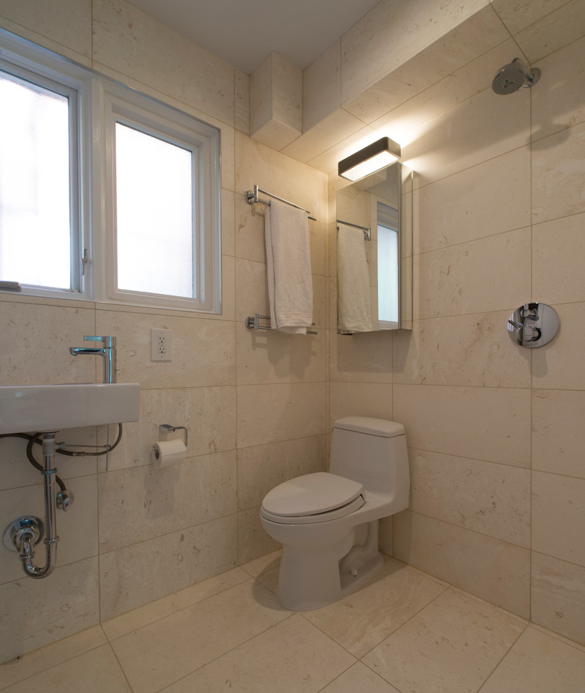 This is an example of a small modern bathroom in DC Metro with a wall-mount sink, a one-piece toilet, beige tile, beige walls, limestone floors and limestone.