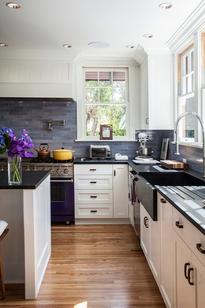 Photo of a traditional l-shaped kitchen in Los Angeles with a farmhouse sink, shaker cabinets, white cabinets, blue splashback, coloured appliances and slate splashback.