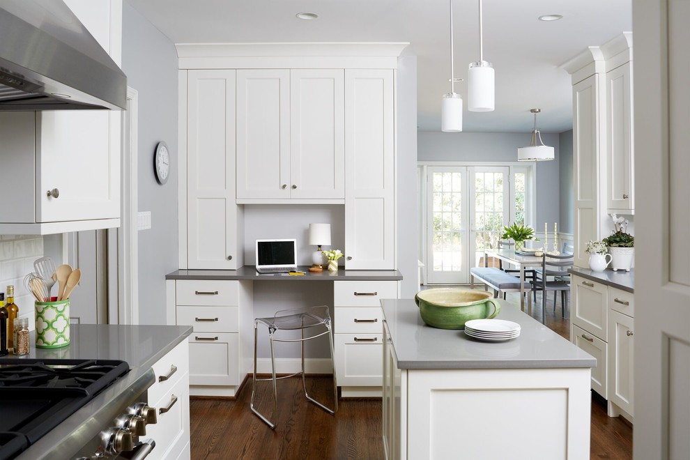 Mid-sized transitional u-shaped dark wood floor and brown floor enclosed kitchen photo in DC Metro with a farmhouse sink, shaker cabinets, white cabinets, solid surface countertops, white backsplash, subway tile backsplash, stainless steel appliances and an island
